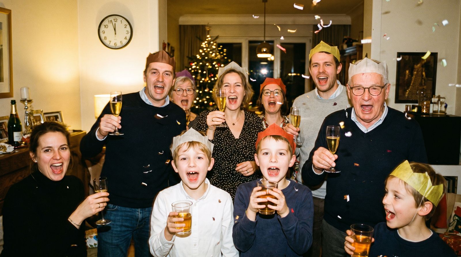 Familie en vrienden tellen af naar middernacht met papieren hoedjes